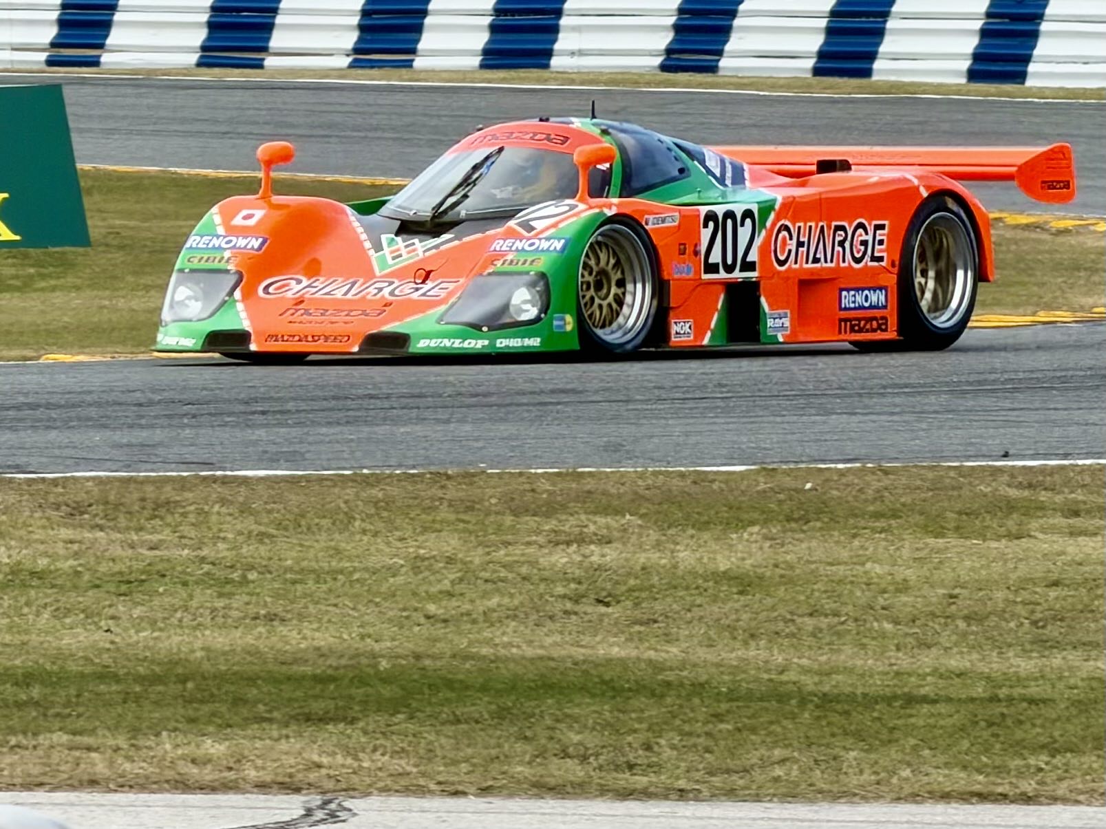 A historic closed-cockpit prototype race car with a huge rear wing on track